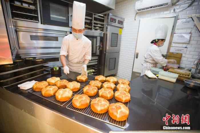 资料图:2月20日,山西太原一面包店,糕点师正在制作糕点。山西餐饮业商家通过线下门店民众进门量体温、消毒、留联系方式,线上外卖配送等多种方式积极防控疫情,逐步开始复工。 中新社记者 张云 摄  中国饭店协会:现金流成餐企最大问题,但未来可期
